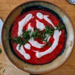A bowl of borscht with yogurt drizzle and chopped dill